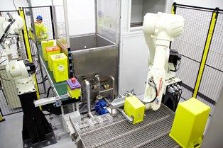 Robotic arms move and empty sharps waste containers before being disinfection